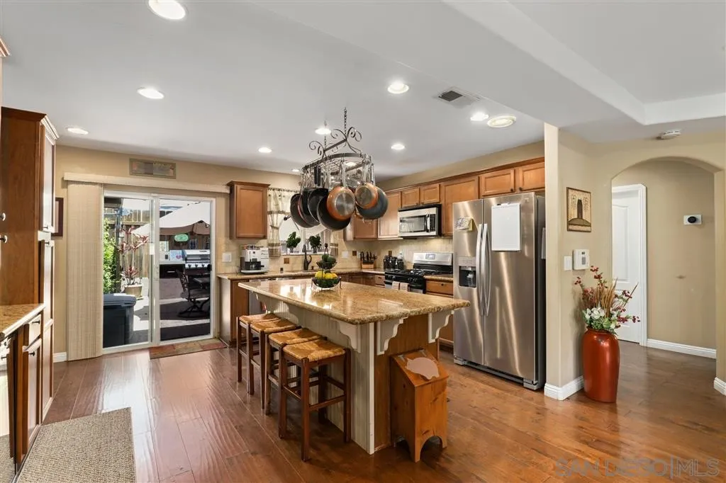 1021 Hillcrest View Lane Fallbrook, CA 92028 - Photo 12 of 24 a kitchen with stainless steel appliances kitchen island granite countertop a refrigerator a stove top oven a dining table and chairs