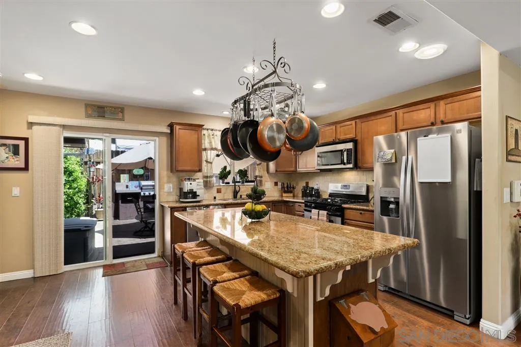 1021 Hillcrest View Lane Fallbrook, CA 92028 - Photo 13 of 24 a kitchen with stainless steel appliances granite countertop a refrigerator a sink dishwasher a dining table and chairs with wooden floor