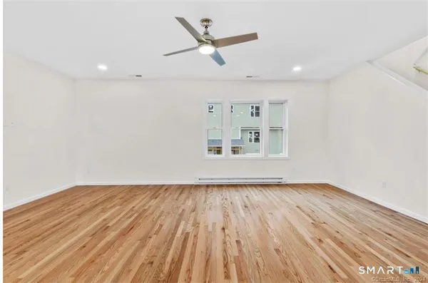 a view of empty room with wooden floor and ceiling fan