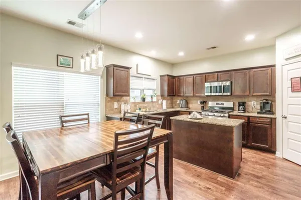 a kitchen with a dining table chairs refrigerator and microwave
