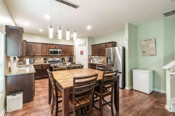 a kitchen with stainless steel appliances granite countertop a stove top oven a sink and dishwasher a refrigerator with wooden cabinets