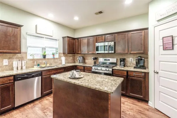 a kitchen with stainless steel appliances granite countertop a sink stove microwave and refrigerator