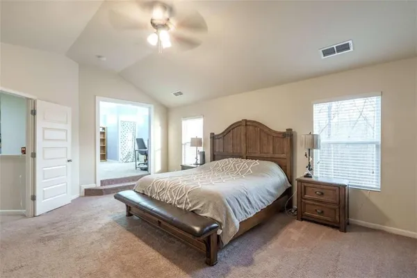 a spacious bedroom with a bed and a flat tv screen on dresser