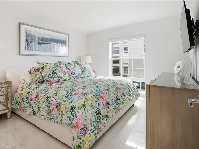 a bedroom with a large bed and a flat tv screen on dresser