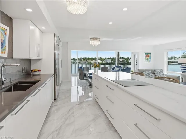 a large white kitchen with a large window and stainless steel appliances