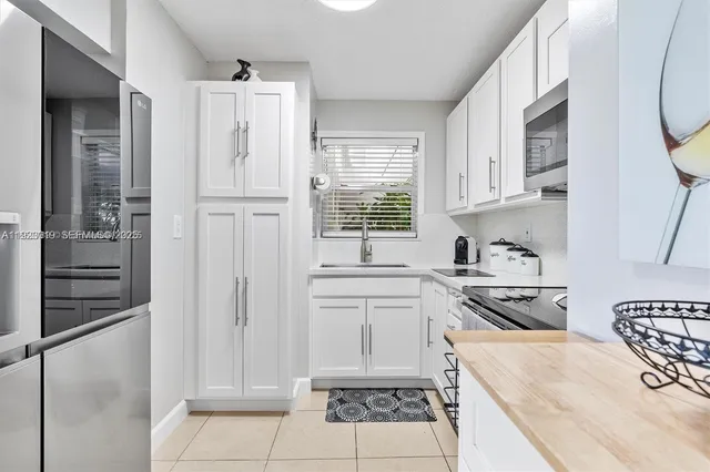 a kitchen with stainless steel appliances granite countertop a refrigerator oven a sink dishwasher and white cabinets with wooden floor