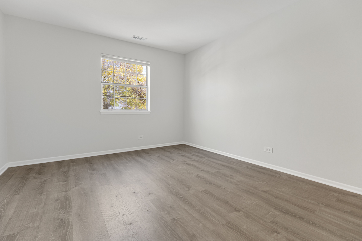 40 South Victoria Lane, Unit G Streamwood, IL 60107 - Photo 11 of 22 an empty room with wooden floor and a window
