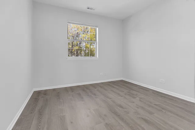an empty room with wooden floor and window