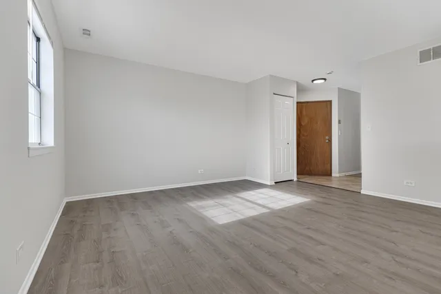 an empty room with wooden floor and windows