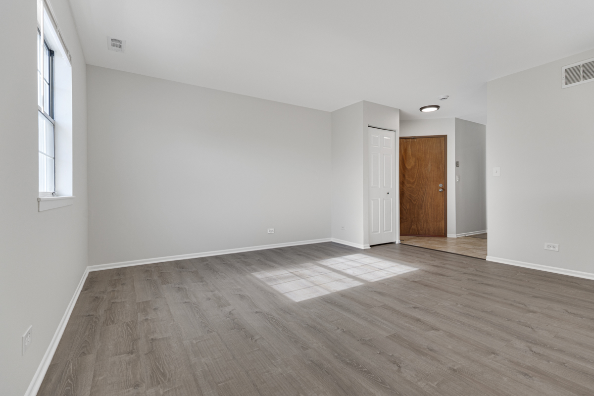 40 South Victoria Lane, Unit G Streamwood, IL 60107 - Photo 2 of 22 an empty room with wooden floor and windows