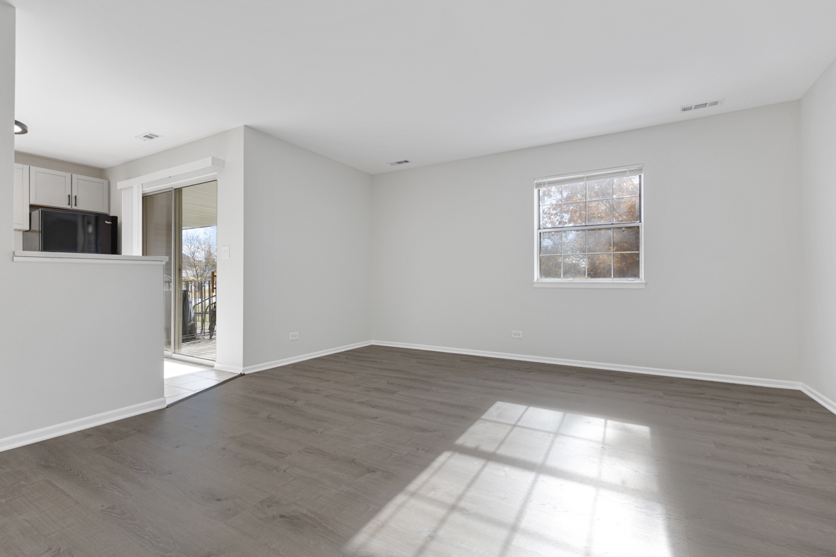 40 South Victoria Lane, Unit G Streamwood, IL 60107 - Photo 4 of 22 a view of an empty room with wooden floor and a window