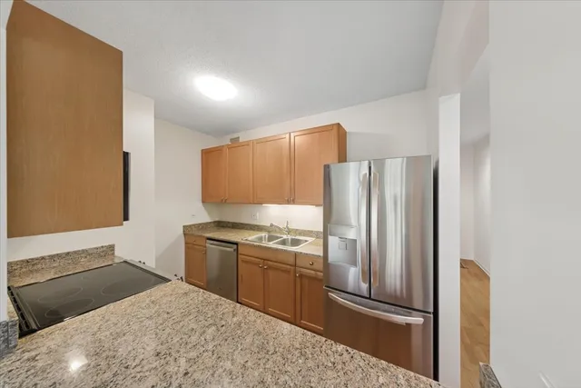 a kitchen with stainless steel appliances granite countertop a refrigerator a stove and a sink