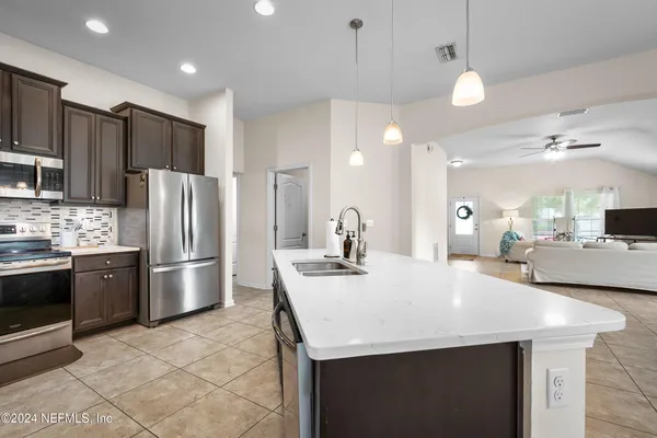 a kitchen with stainless steel appliances kitchen island granite countertop a sink a stove a refrigerator and island with wooden floor