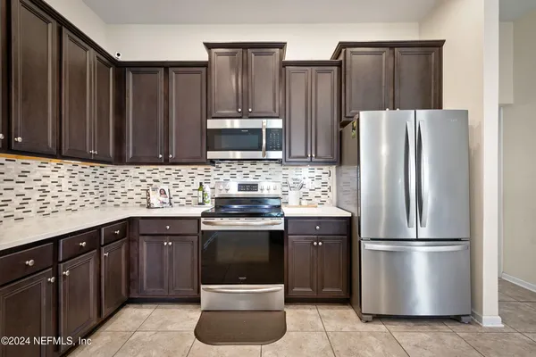 a kitchen with stainless steel appliances granite countertop a refrigerator a stove a sink and a microwave