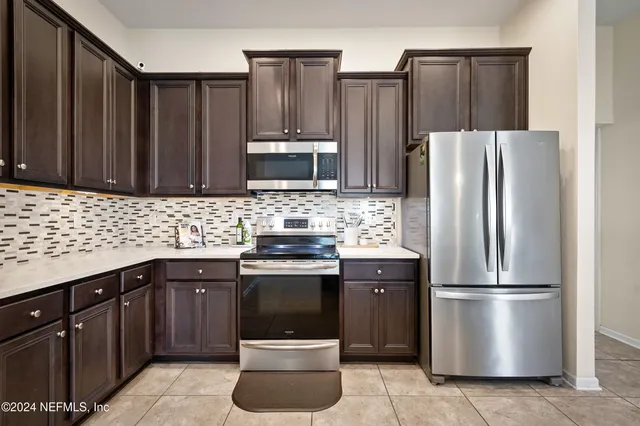 a kitchen with stainless steel appliances granite countertop a refrigerator a stove a sink and a microwave