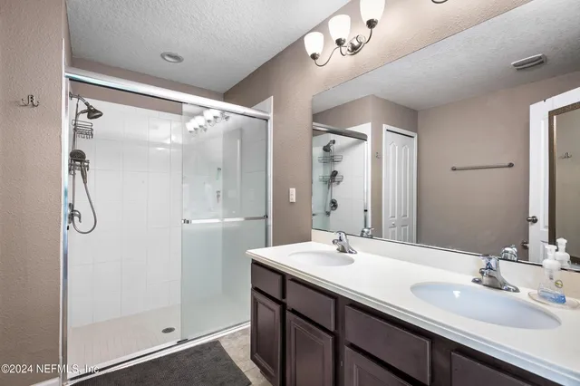 a bathroom with a double vanity sink mirror and shower