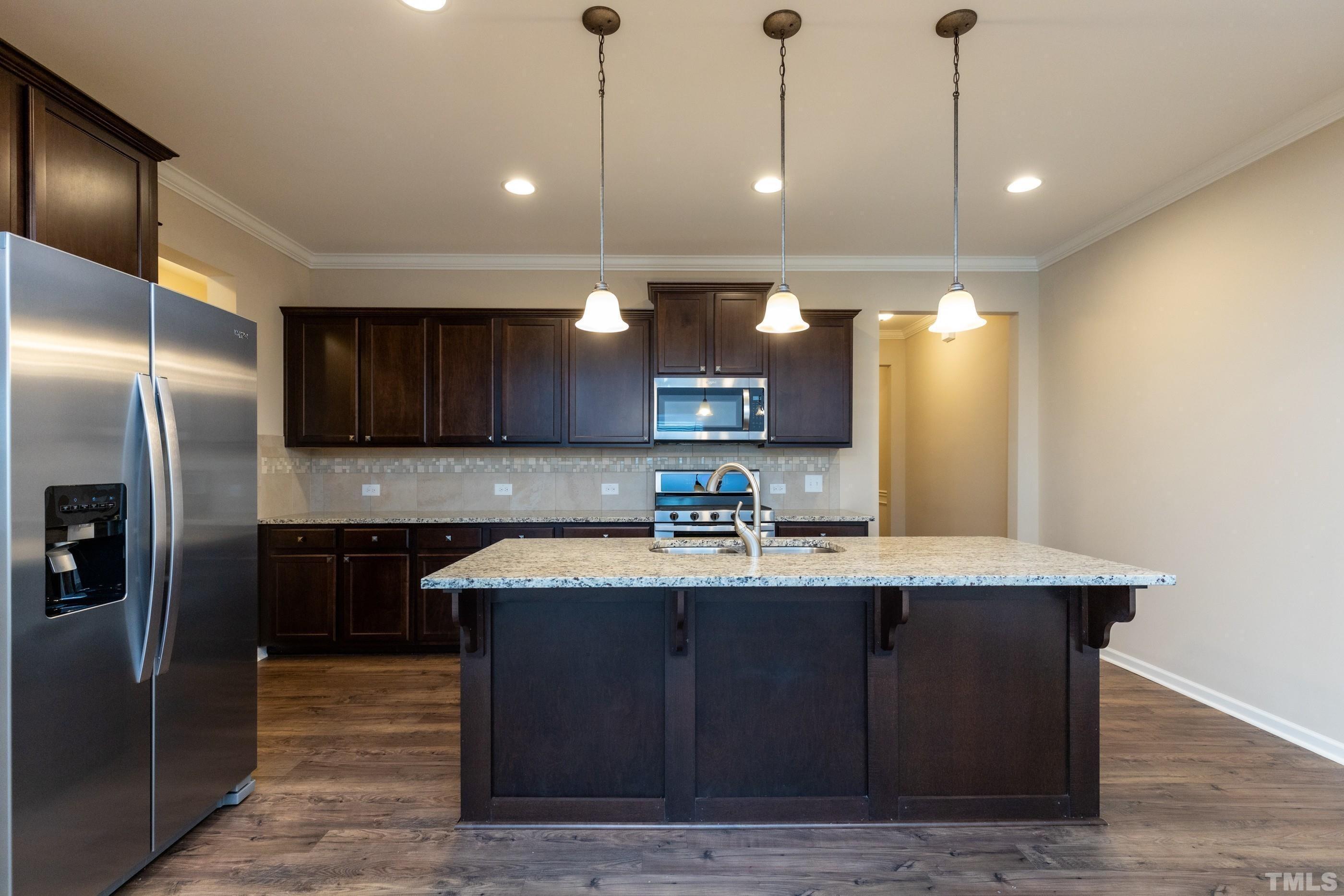 566 Chessie Station Apex, NC 27502 - Photo 5 of 29 a kitchen with stainless steel appliances granite countertop a sink a stove and a refrigerator