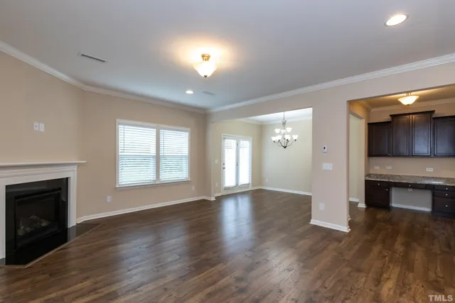 an empty room with wooden floor a fireplace and windows