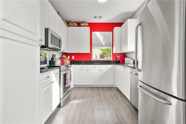 a kitchen with stainless steel appliances granite countertop a stove a sink and a microwave