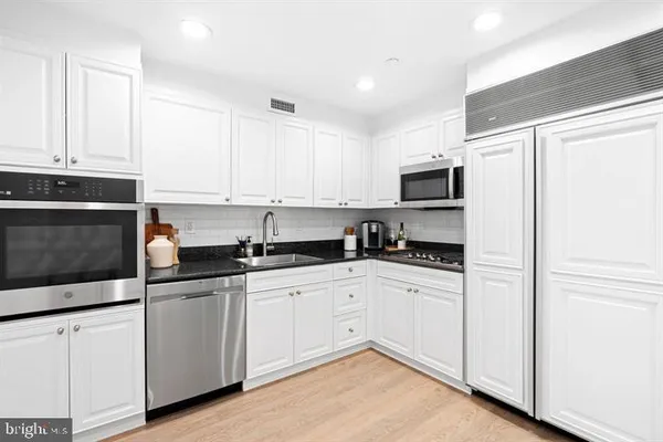 a kitchen with granite countertop white cabinets and white appliances