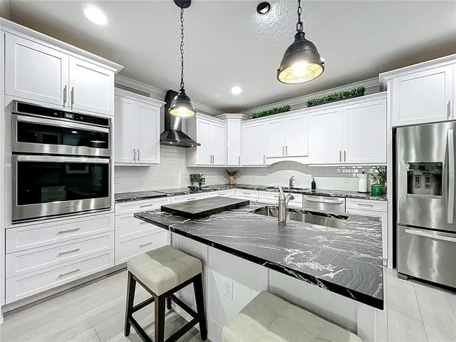 a kitchen with stainless steel appliances granite countertop a stove and a wooden floors