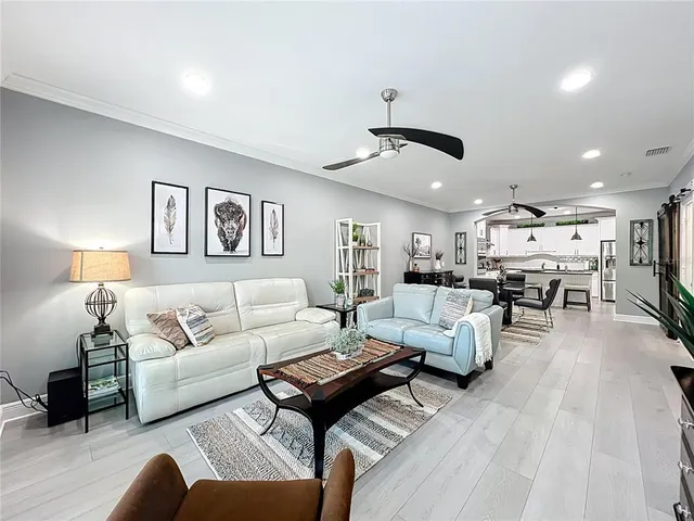 a living room with stainless steel appliances kitchen island granite countertop furniture and a wooden floor