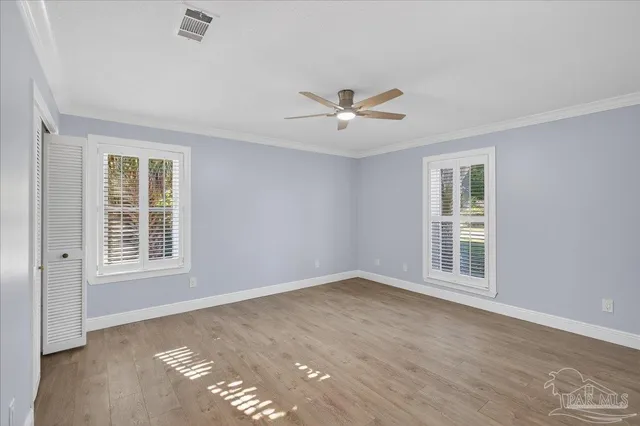 an empty room with wooden floor and windows
