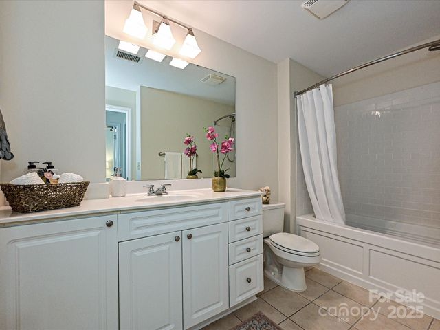 a spacious bathroom with a double vanity sink a large mirror a toilet and a shower