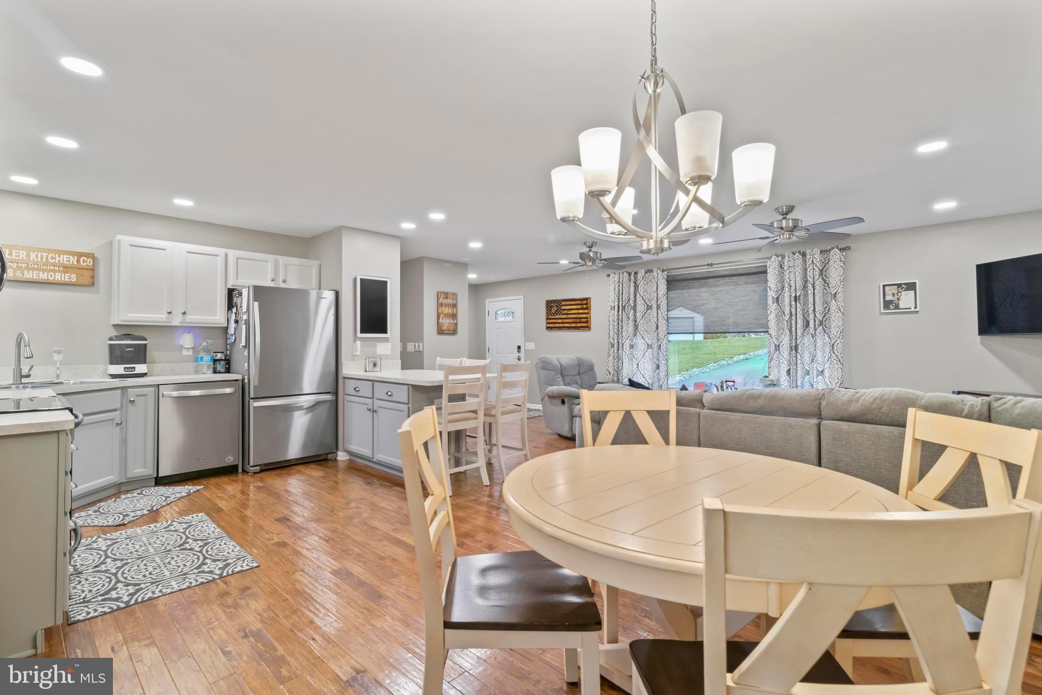 44350 Clarkes Landing Road Hollywood, MD 20636 - Photo 14 of 39 a kitchen with stainless steel appliances kitchen island granite countertop a refrigerator a stove a sink dishwasher a dining table and chairs with wooden floor