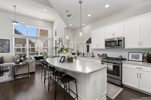 a kitchen with stainless steel appliances granite countertop a stove refrigerator a microwave oven a dining table and chairs with wooden floor