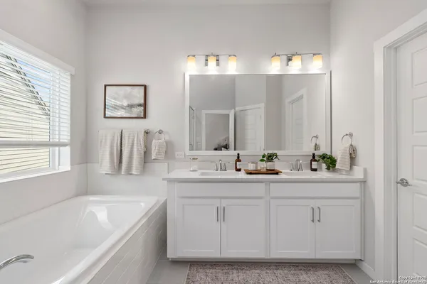a bathroom with a bathtub a double vanity sink and mirror