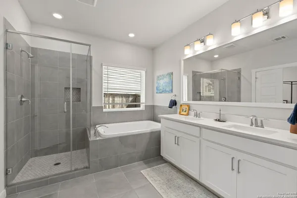 a bathroom with a tub a sink shower and mirror