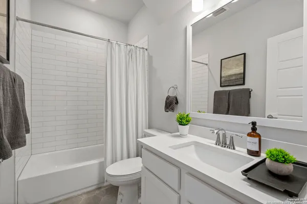 a bathroom with a granite countertop sink a toilet a mirror a vanity and shower