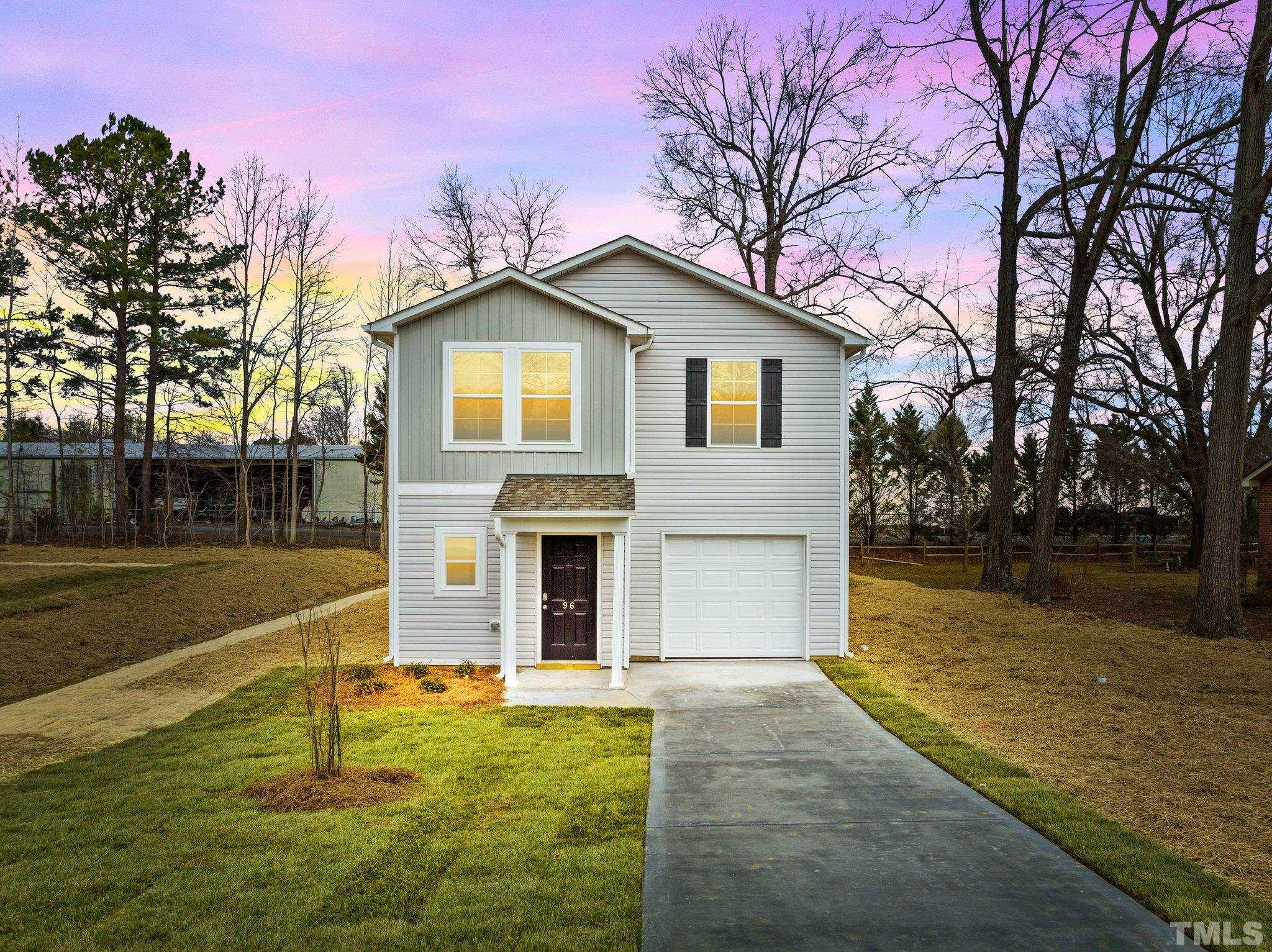 a front view of house with yard and trees in the background