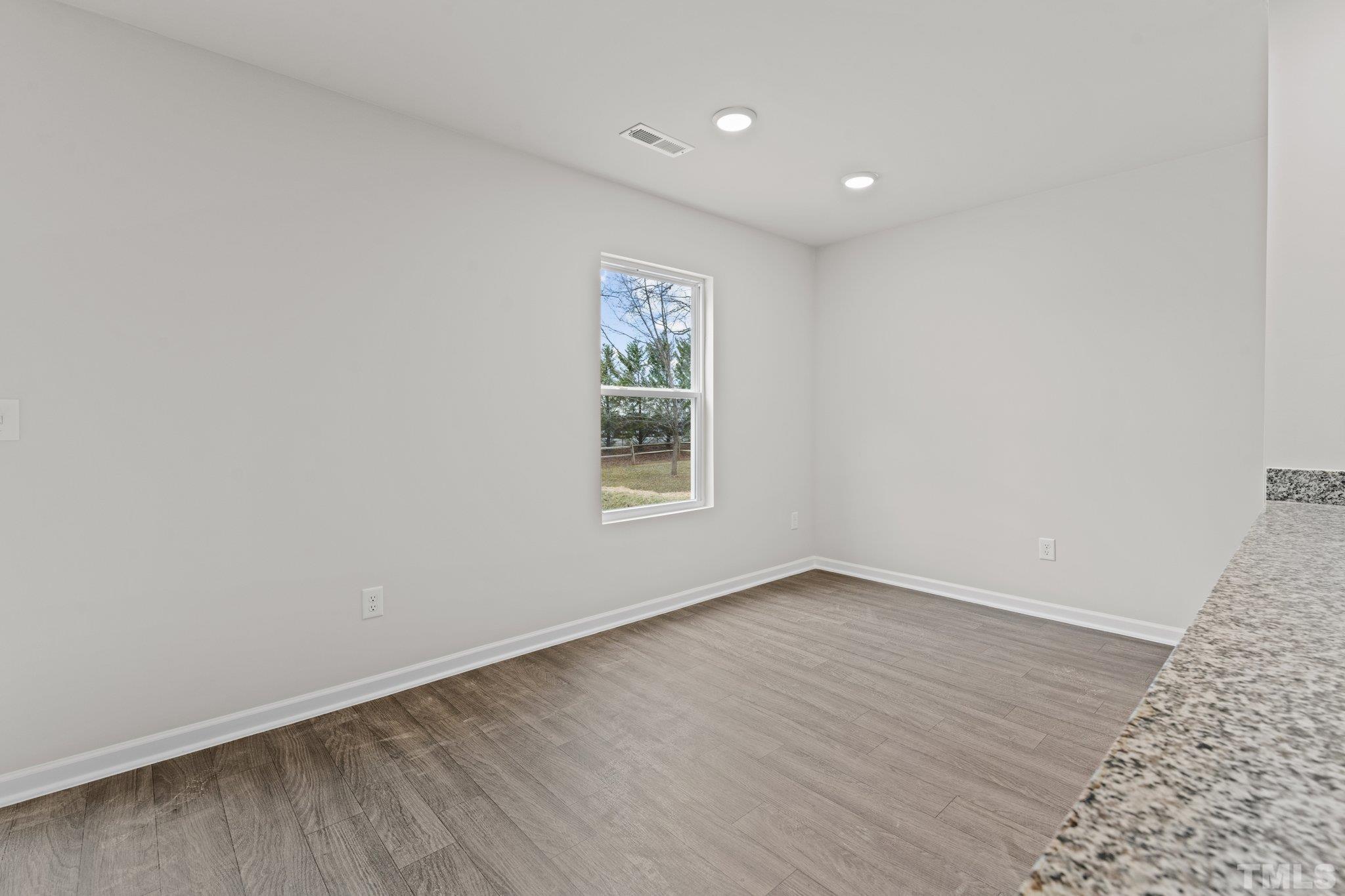 96 Somerset Drive Roxboro, NC 27573 - Photo 12 of 29 an empty room with wooden floor and windows