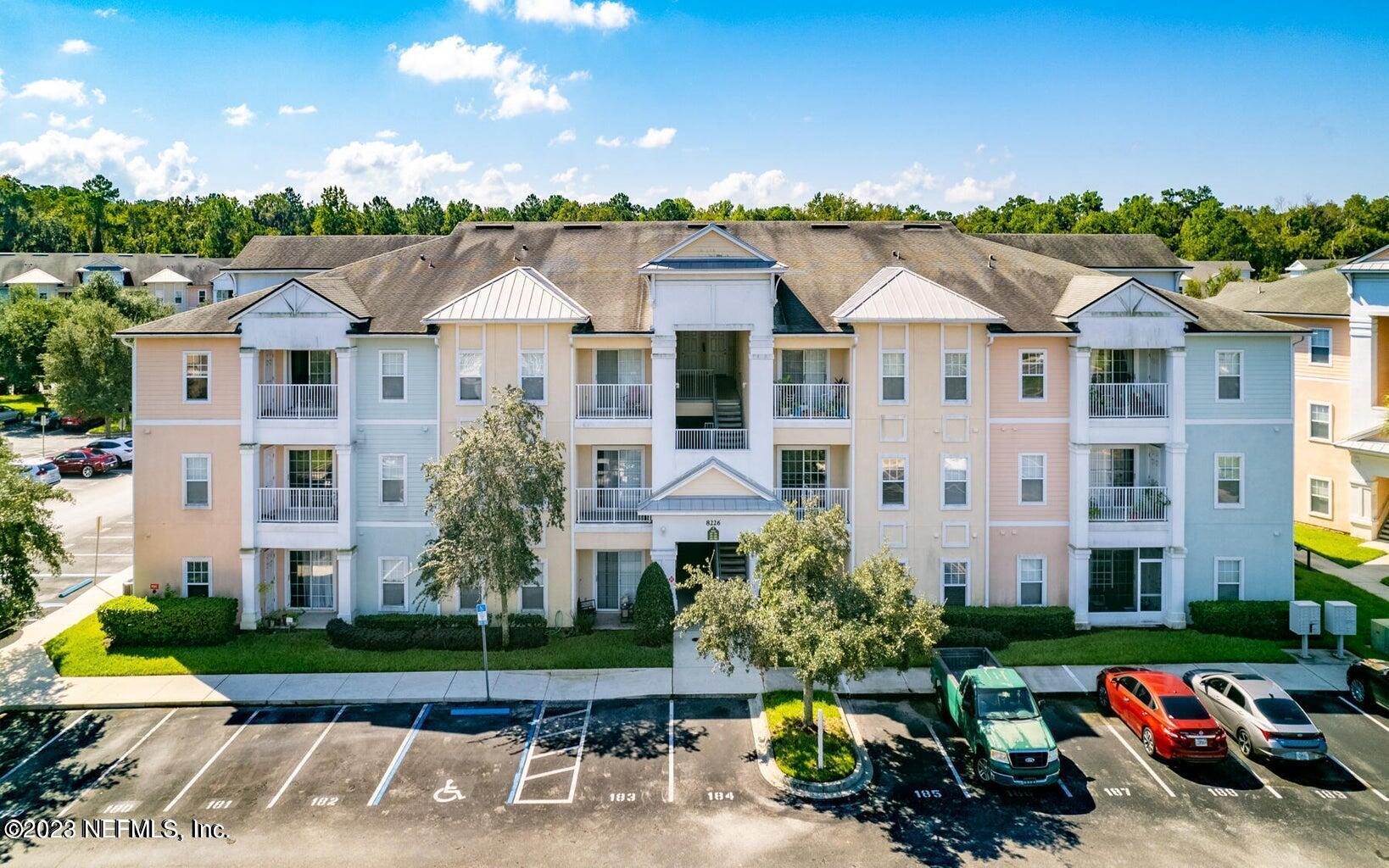 8226 Green Parrot Road, Unit 308 Jacksonville, FL 32256 - Photo 22 of 31 a view of a white house with a yard and table and chairs under an umbrella