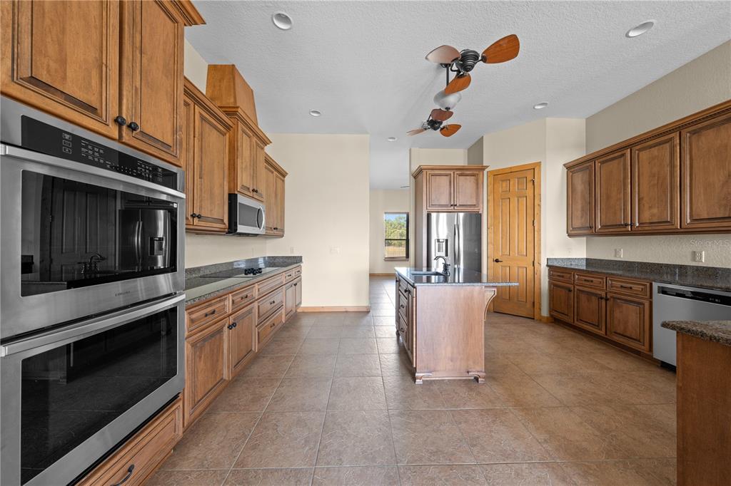 3911 Story Road St. Cloud, FL 34772 - Photo 16 of 97 a kitchen with stainless steel appliances granite countertop a stove top oven a sink dishwasher and cabinets with wooden floor