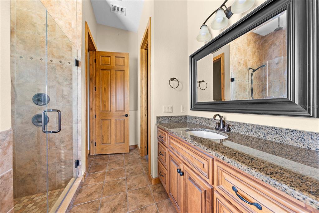 3911 Story Road St. Cloud, FL 34772 - Photo 29 of 97 a bathroom with a granite countertop sink mirror and shower