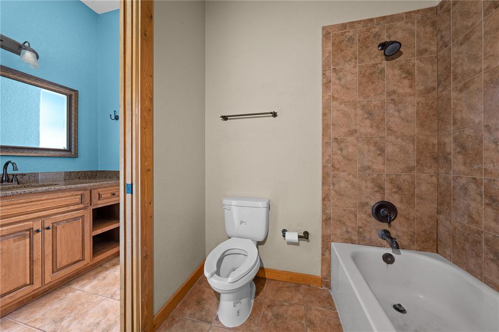 3911 Story Road St. Cloud, FL 34772 - Photo 61 of 97 a bathroom with a granite countertop toilet a sink and bathtub