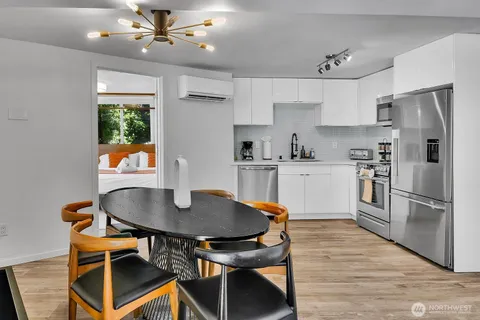 a kitchen with stainless steel appliances granite countertop a sink a stove a refrigerator dining table and chairs with wooden floor