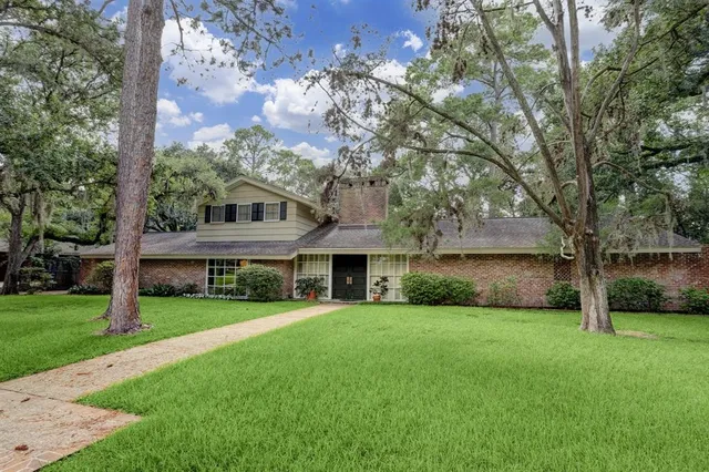 a view of house with a big yard and large trees