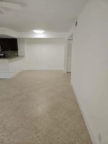a view of an empty room with a kitchen space and a window