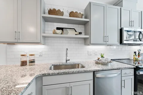 a kitchen with granite countertop a sink stove and cabinets