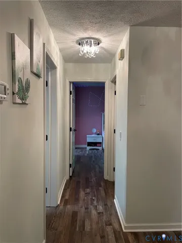 a view of a hallway with wooden floor and a bathroom