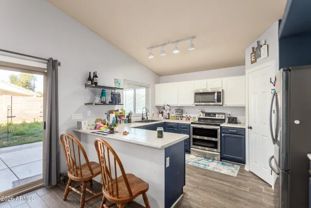 a kitchen with stainless steel appliances a stove a sink dishwasher a refrigerator white cabinets and wooden floor