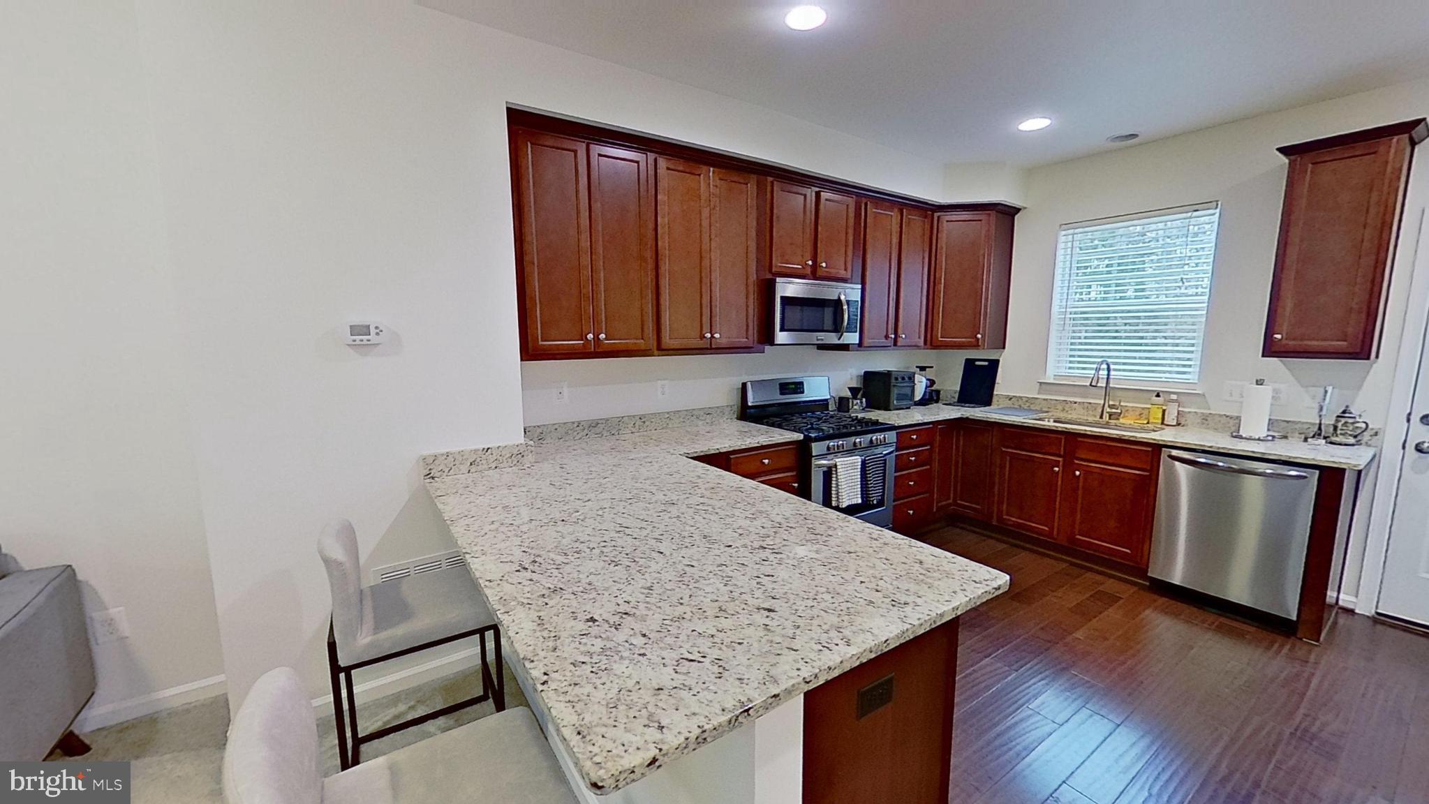 23340 Starry Way California, MD 20619 - Photo 7 of 18 a kitchen with a sink a stove a microwave a center island and a window