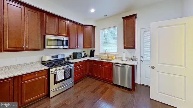 a kitchen with stainless steel appliances granite countertop a stove a sink dishwasher and a microwave oven with wooden floor