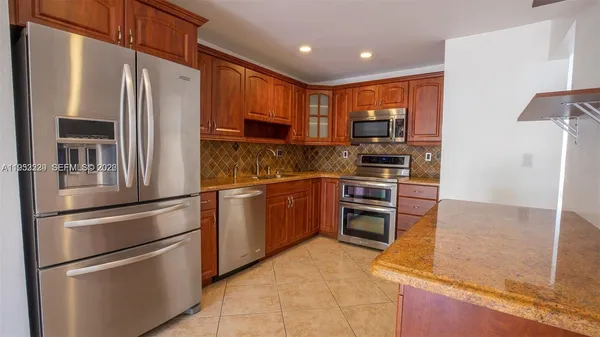 a kitchen with stainless steel appliances granite countertop a refrigerator and a stove