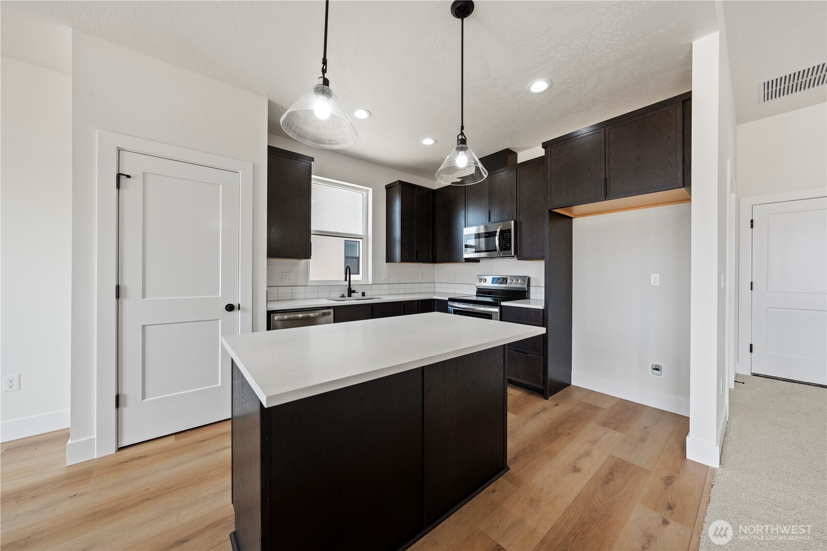 1111 E Mount Othello, WA 99344 - Photo 9 of 34 a kitchen with kitchen island a sink stainless steel appliances and wooden floor