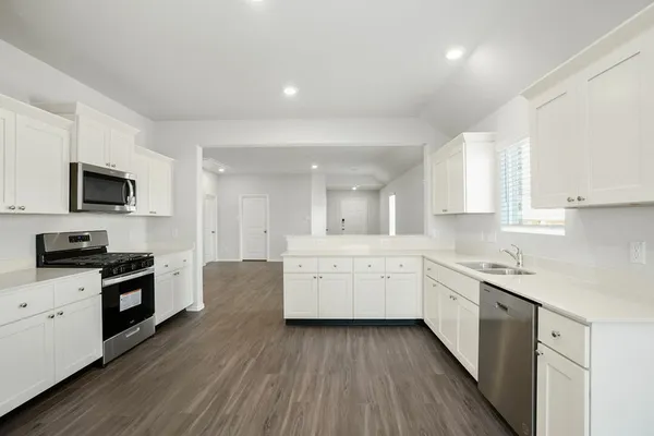 a large kitchen with a lot of counter space and wooden floor